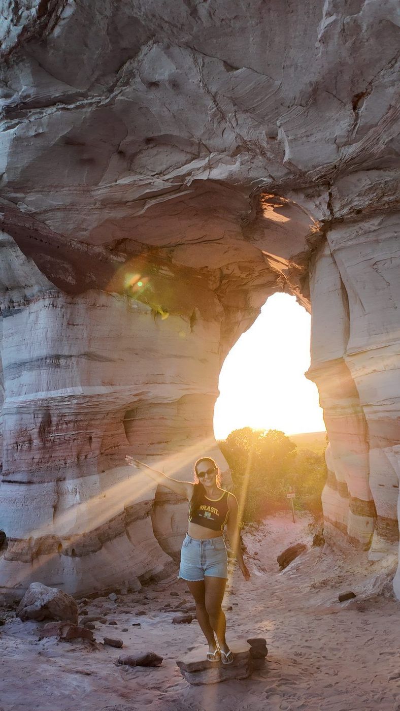 Isadora na Pedra Furada, com o sol atravessando a rocha