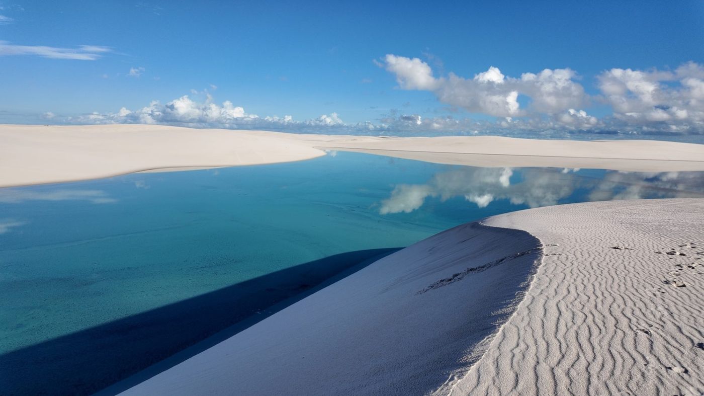 Grupo de mulheres caminhando pelas dunas dos Lençóis Maranhenses ao entardecer